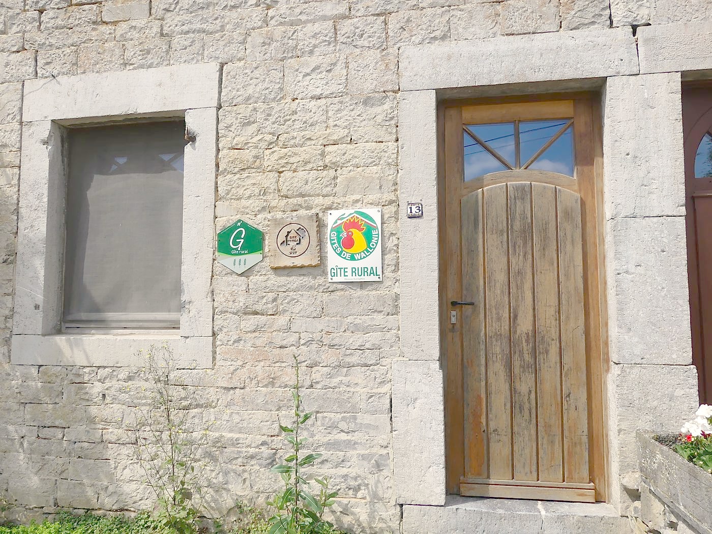 Façade en pierre du Biogîte à l'arrivée, numéro 13 et labels muraux
